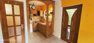 a kitchen with a clock on the wall and a door at Kis ház az erdő mellett - Little house next to the forest in Balatonakarattya
