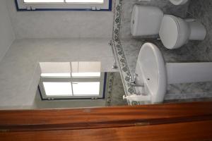 łazienka z toaletą, umywalką i oknem w obiekcie Andar com jardim e estacionamento w mieście Paço de Arcos
