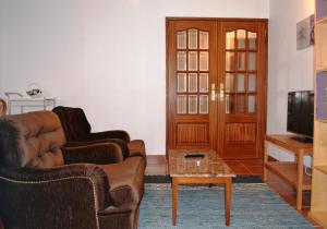 a living room with two leather chairs and a tv at Andar com jardim e estacionamento in Paço de Arcos