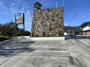 een stenen muur en een bord op een parkeerplaats bij Sierra Lodge Three Rivers in Three Rivers