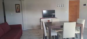 a living room with a table and a tv at Alfa & Omega Departamentos Turísticos in Dina Huapi