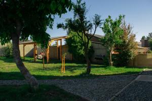 a house with two trees in the yard at Alfa & Omega Departamentos Turísticos in Dina Huapi