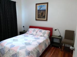 a bed with a colorful comforter and a chair in a bedroom at Townhouse 3 in Broken Hill