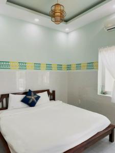 a bedroom with a large white bed with blue pillows at Hacoda Homestay in Con Dao
