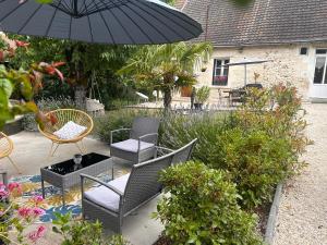 a patio with chairs and an umbrella and plants at Gîte le bas ray près de Beauval in Veuil