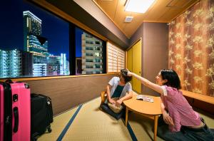 Eine Frau, die an einem Tisch sitzt und einem Mann die Haare schneidet. in der Unterkunft COGO TENNOJI in Osaka