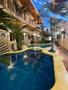 a large swimming pool in a building with palm trees at Bungalows Las Glorias in Rincon de Guayabitos