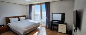 a bedroom with a bed and a television and a balcony at Mud Beach Hotel in Boryeong
