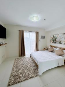 Un dormitorio blanco con una cama grande y una ventana en CF Haven - Resort Living Condo w/ Balcony at Bamboo Bay, en Mandaue