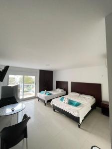 a bedroom with two beds and a desk and a television at Hotel Fundacooedumag Rodadero in Santa Marta