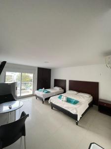 two beds in a large room with a window at Hotel Fundacooedumag Rodadero in Santa Marta