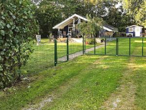 a fence in front of a yard with a house at 8 person holiday home in Juelsminde in Sønderby
