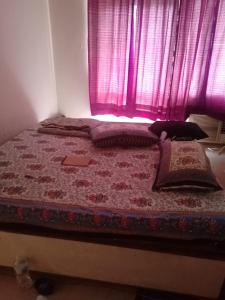 a bed in a bedroom with a pink window at 2BHKapartment-Calm and natural in Faridabad