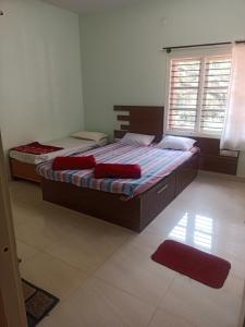 two twin beds in a bedroom with a window at Chikmagalur cool stay in Chikmagalūr