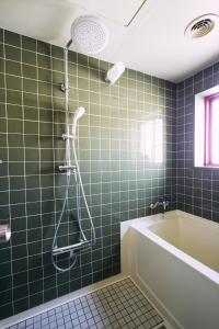 baño de azulejos verdes con bañera y ducha en 「まちの隠れ家ペントハウス」ロフトベッド付き！｜ STAY UWU 003 Penthouse, en Kochi