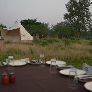 a table with plates and glasses and a tent at Burhan Wilderness Camps in Bhurkīā