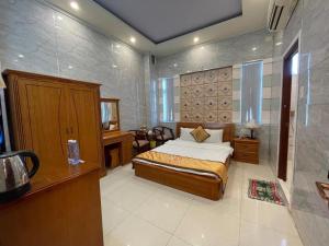 a bedroom with a bed and a desk in a room at Hồng Nhung Hotel Kiên Giang in Rạch Giá