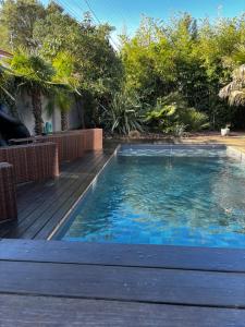 a swimming pool next to a wooden deck at Villa des 4 vents in Capbreton