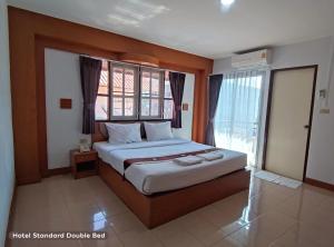 1 dormitorio con 1 cama grande y ventana en โรงแรมอารีน่ารีสอร์ท อุตรดิตถ์, en Uttaradit