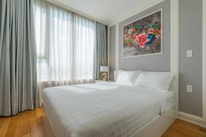 a bedroom with a large white bed and a window at Léman Luxury Apartment District 3 HCMC in Ho Chi Minh City