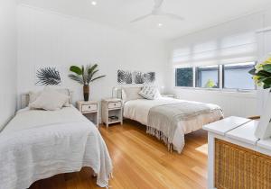 two beds in a room with white walls and wood floors at Saltwater in Gerringong