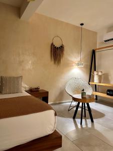 a bedroom with a bed and a chair and a table at Casa Bicachi - Adults Only in Puerto Escondido