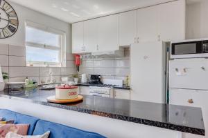 a kitchen with white cabinets and a large clock on the wall at Miracle Miranda Sydney Apartment in Miranda