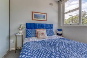 a blue bed in a bedroom with a window at Miracle Miranda Sydney Apartment in Miranda