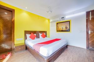 a bedroom with a bed and a yellow wall at OYO Hotel Carol Garden in New Delhi