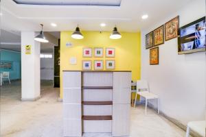 a room with yellow walls and a counter and chairs at OYO Hotel Carol Garden in New Delhi