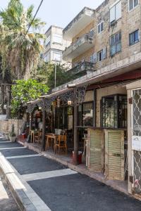a store on the side of a street with tables and chairs at Sea&stone Apartment in Haifa