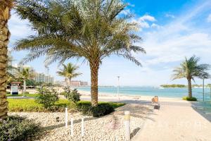 een uitzicht op een strand met palmbomen en de oceaan bij LUX Opulent Island Suite Burj Khalifa View 7 in Dubai