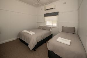 Duas camas num pequeno quarto com uma janela. em The Centennial Hotel Gulgong em Gulgong