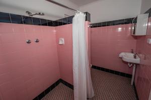 a pink bathroom with a shower and a sink at The Centennial Hotel Gulgong in Gulgong