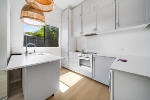 a white kitchen with a sink and a window at Spacious 4-bed Family Home in Tranquil Setting in Canberra