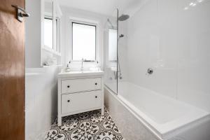 a white bathroom with a sink and a shower at Spacious 4-bed Family Home in Tranquil Setting in Canberra