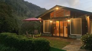 uma pequena casa com uma mesa e um guarda-chuva em Los Lagos Lodge em San Gerardo de Dota