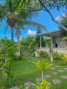 a garden with palm trees and a house at Gapul pinpilinPauxa in Nusa Penida