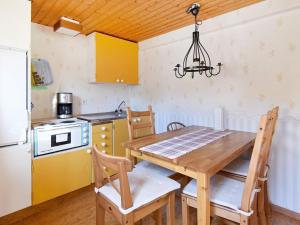 uma cozinha com uma mesa de madeira com cadeiras e um lustre em 5 person holiday home in BRASTAD em Brastad