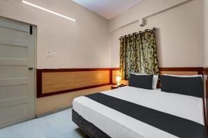 a bedroom with a bed with a door and a window at SPOT ON Benaka Delux Lodging & Delux Rooms in Bangalore