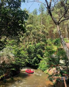 a group of people riding a red raft down a river at Camping muara rahong hills in Palayangan