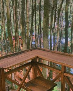 a wooden bench on a deck in the woods at Camping muara rahong hills in Palayangan