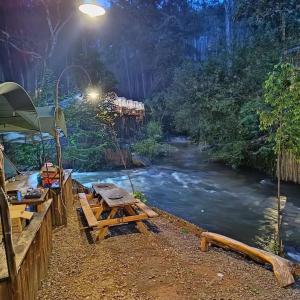 a river with a picnic table next to a river at Camping muara rahong hills in Palayangan