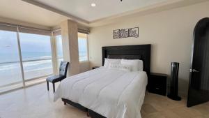 a bedroom with a bed with a view of the ocean at Beautiful Beach Front Condo near Downtown in Rosarito