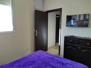 a bedroom with a purple bed and a dresser at Maison de vacances in Ifrane