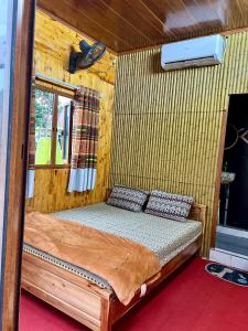een slaapkamer met een bed in een houten hut bij Pura Homestay in Na Thôn