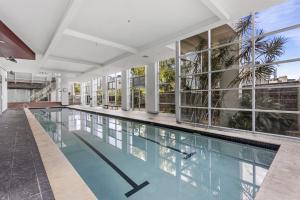 an indoor swimming pool in a building with a large window at High-Floor 2-Bed CBD Unit With Views & Amenities in Brisbane