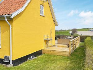 une maison jaune avec une terrasse en bois à côté dans l'établissement 6 person holiday home in Tranek r, à Tranekær