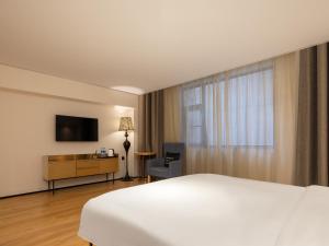 a hotel room with a bed and a television at Waito Hotel Yuexiu Park Guangzhou in Guangzhou