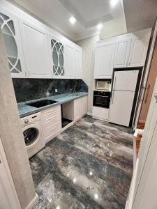 uma cozinha com armários brancos e uma máquina de lavar e secar roupa em London House Apartment em Baku